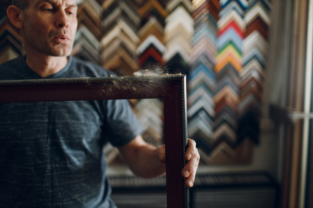 制定车间。大师在画室吹掉法式面包手工相框的灰尘图片下载