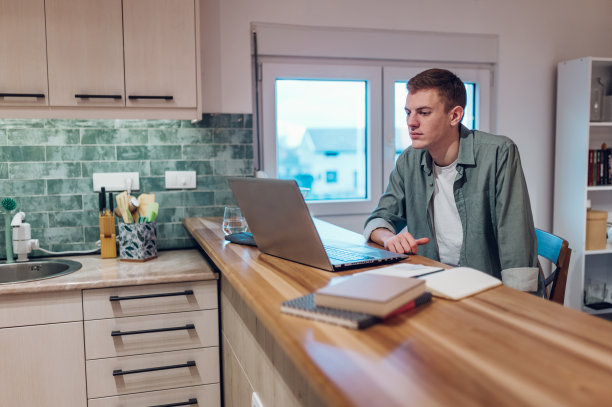 男人在家工作时在厨房里用笔记本电脑图片下载