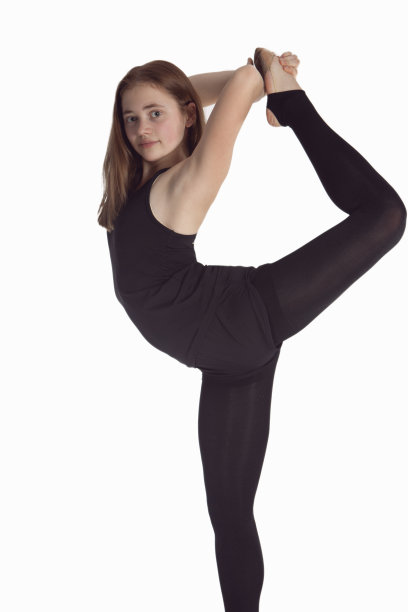 体育的概念。白人艺术体操运动员运动员在训练服装的肖像，在她的腿分裂肌肉伸展对抗白色。图片下载