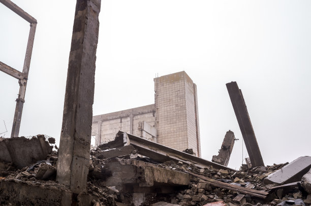 一堆混凝土瓦砾和建筑残骸，巨大的混凝土梁映衬着建筑的残骸和灰蒙蒙的天空。背景图片下载