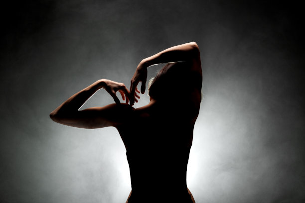 剪影现代芭蕾舞演员摆姿势在黑暗的背景与烟图片下载