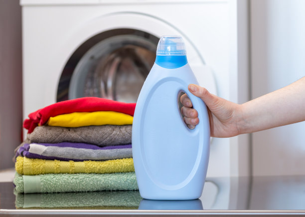 女人手里拿着一瓶洗涤剂和一堆衣服图片下载