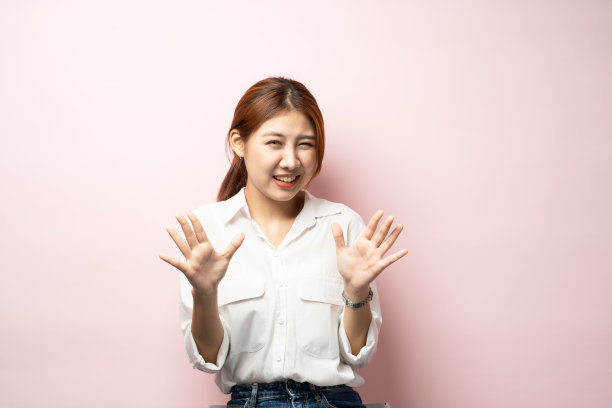 微笑可爱的亚洲女孩感觉尴尬拒绝朋友，举手投降或拒绝，笑着说对不起不会来，否认或不赞成某事，粉红色背景。图片下载