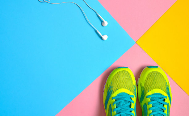 俯视图跑步运动鞋和跳过白色耳机在粉红色，蓝色和黄色粉彩背景，文本复制空间。平的。运动，健身理念，健康生活方式图片下载