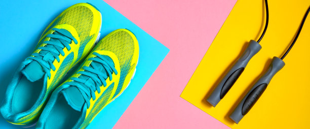 运动设备与跑步鞋和跳绳在粉红色，蓝色和黄色粉彩背景，文本复制空间。俯视图，平躺。运动，健身理念，健康生活方式图片下载