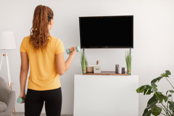 用哑铃锻炼的女士在家看电视，后视镜图片下载