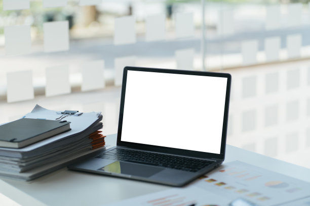 侧视图的办公桌面与空白笔记本电脑和各种办公工具在木头桌上。图片下载