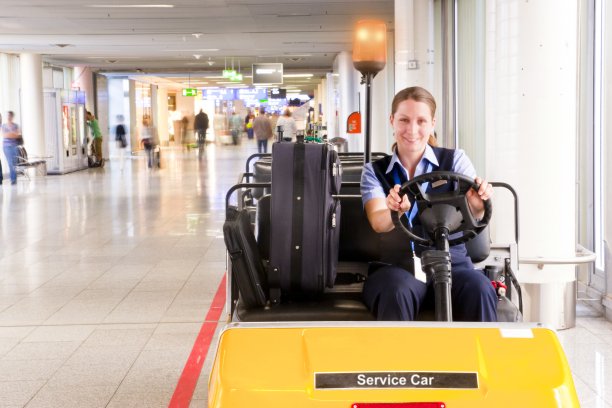 开朗的机场女员工，带着一辆电动服务车图片下载