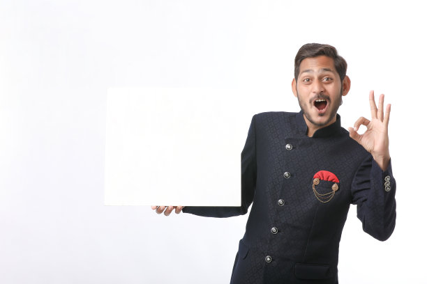 印度男子手持白板，在节日期间穿着传统服装，站在白色背景上推销商品。图片下载