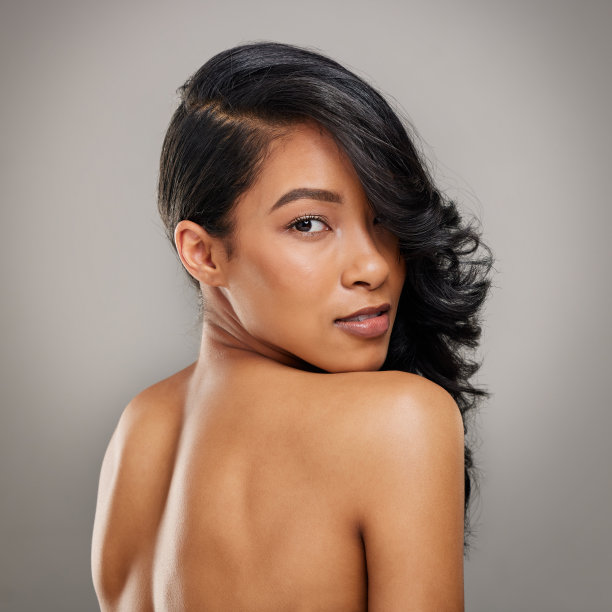 一个美丽的年轻女子在灰色的背景下摆姿势图片下载