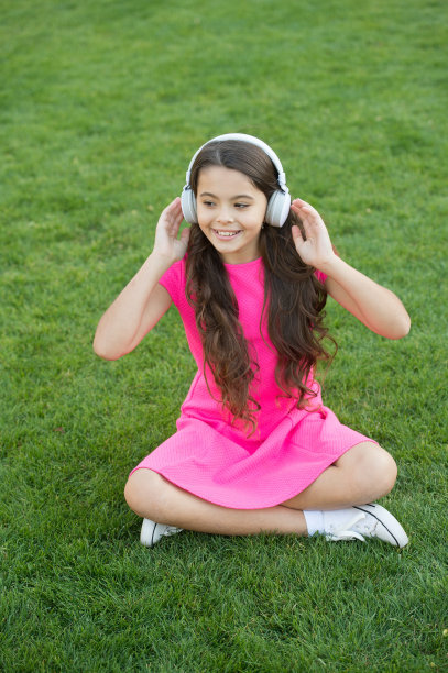 环境声耳机。快乐的孩子在户外听音轨。小女孩喜欢戴着耳机听音乐。高保真立体声。新技术。现代生活。放松的声音。夏天冷静下来图片下载