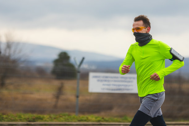 一个年轻男性跑步者的特写穿着充满活力的跑步衣服和跑步太阳镜，在雨天和阴天跑步图片下载