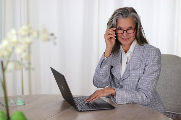 成熟漂亮的女人，戴着眼镜在笔记本电脑上工作图片下载