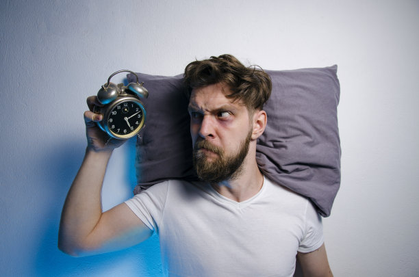 一夜未眠后，愤怒的男人看着闹钟图片下载