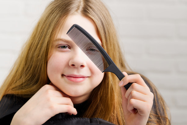 漂亮女孩的肖像扮演理发师和想象在镜子前。图片下载