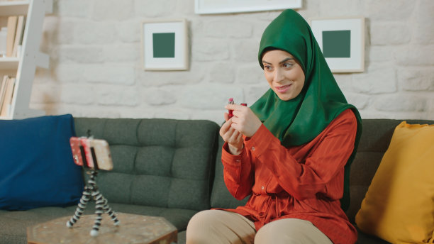 一位年轻的博主戴着头巾，通过视频会议向顾客介绍产品。图片下载