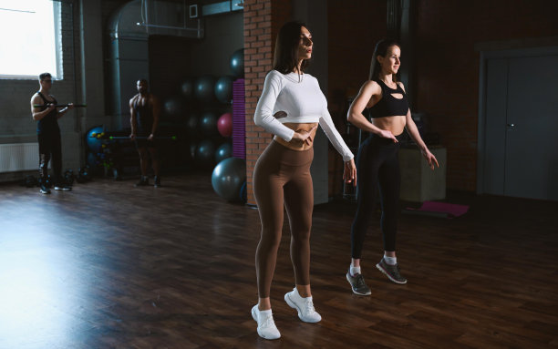 两名年轻的成年白人女性在健身或健康比赛前对着镜子练习摆姿势。图片下载