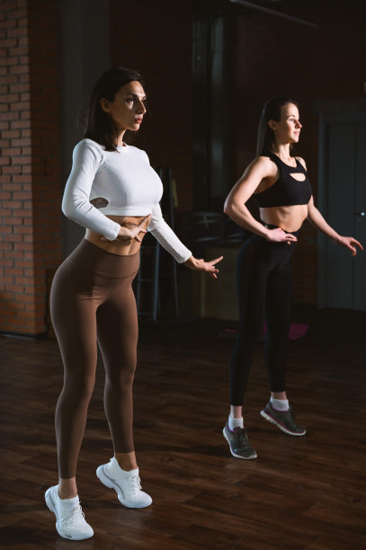 两名年轻的成年白人女性在健身或健康比赛前对着镜子练习摆姿势。图片下载