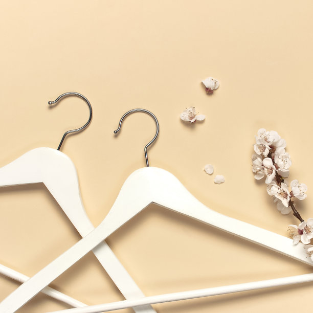 创意春季销售理念。白色木制衣架与杏花春天小枝米色背景顶视图平躺。时尚春季折扣购物销售商店促销设计极简主义图片下载