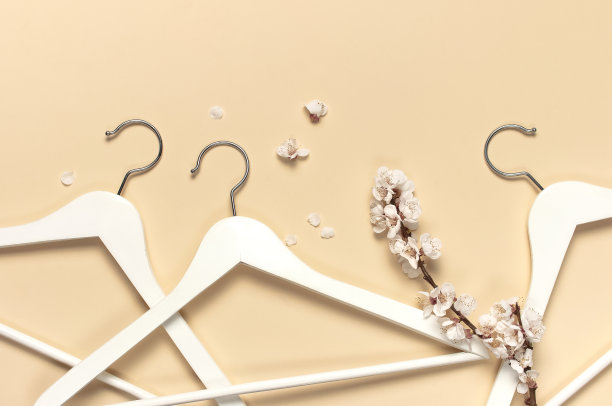 创意春季销售理念。白色木制衣架与杏花春天小枝米色背景顶视图平躺。时尚春季折扣购物销售商店促销设计极简主义图片下载