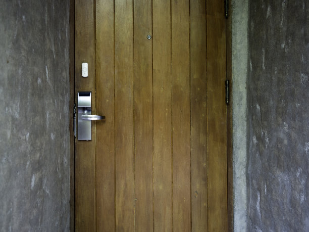 复古的棕色木门，带有现代电子钥匙卡锁系统，智能非接触式钥匙卡面板，水泥墙上的把手上有门铃。酒店门房的电气控制。图片下载