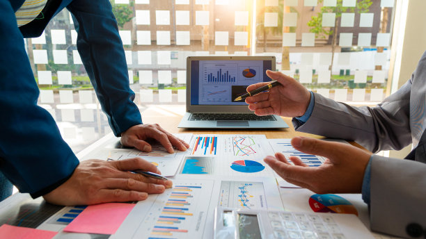 一群商人开会分析财务图表数据，为商业会计计划出谋划策。在办公室的桌子上放一个笔记本电脑和一个计算器。图片下载