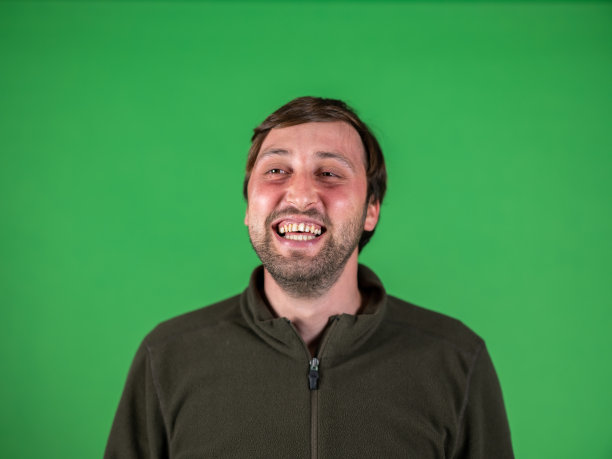 一个年轻微笑的男人在绿色背景的肖像图片下载