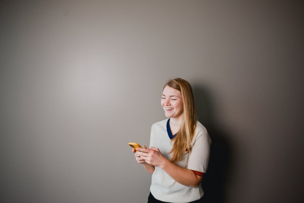 金发女人在她的智能手机上发短信图片下载