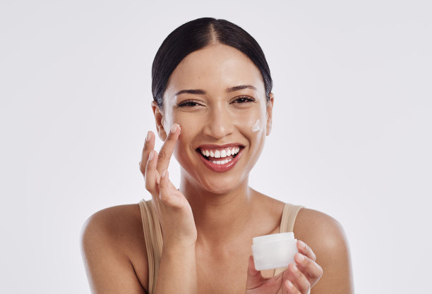 一个漂亮的年轻女人正在涂面霜图片下载