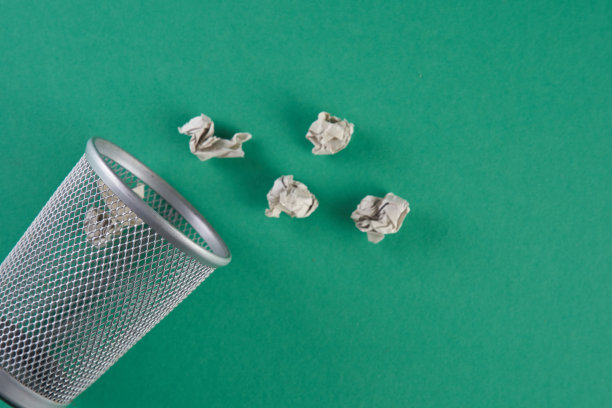 垃圾桶装满了碎纸，倒在一边，孤立在绿色背景上图片下载