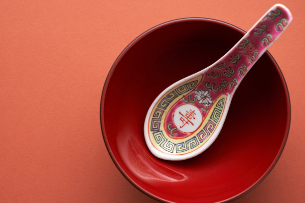 中国设计的勺子和红色的碗在红色的背景上图片下载