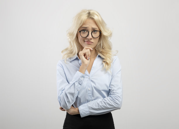 决策。沉思的女商人的肖像，戴着眼镜看着相机和触摸下巴，灯光背景图片下载