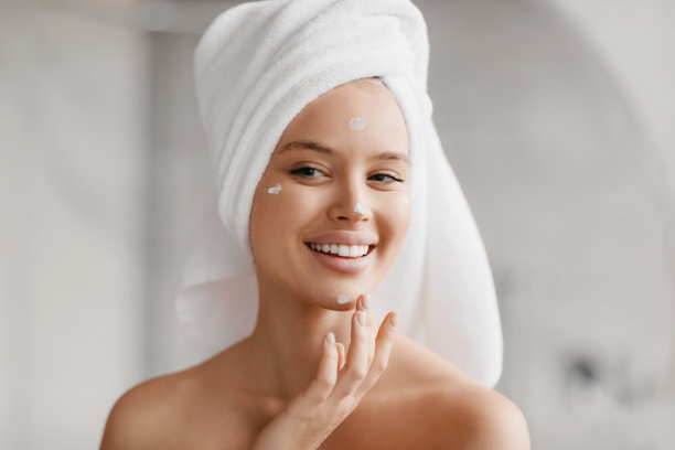 健康肌肤，护理保湿理念。快乐的白种人女士用毛巾在头上涂面霜图片下载