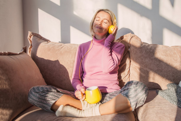 带着耳机，闭着眼睛微笑的成年女人图片下载