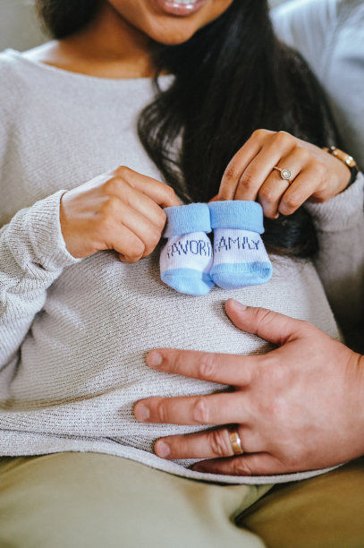 这张照片拍摄的是一个不认识的女人，她怀孕的肚子上穿着婴儿鞋，和她的丈夫坐在家里图片下载