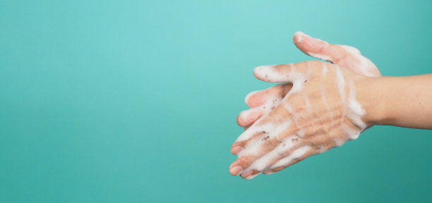 在薄荷绿和蒂芙尼蓝的背景上用起泡的肥皂洗手。图片下载