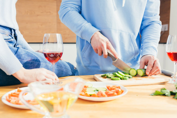 一个女人和一个男人的手的特写照片准备食物，厨房桌子上的沙拉，酒，蔬菜，水果，图片下载