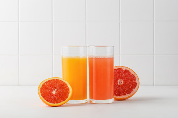 两杯鲜榨果汁放在白色桌子上。菜单上有红橙汁和西柚汁。模拟了图片下载