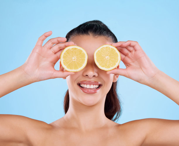 一名迷人的年轻女子在蓝色背景下摆出两个柠檬的姿势图片下载