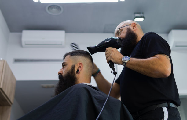 男性理发师为他的客户烘干和梳理头发图片下载