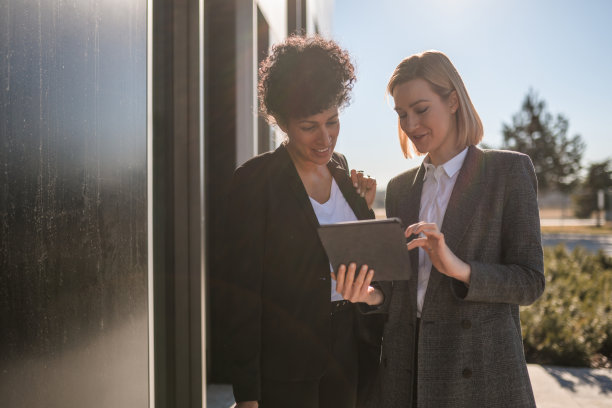 女性商务同事在户外讨论时使用数码平板电脑图片下载
