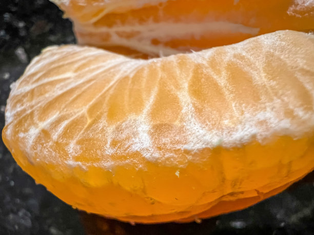 带黑色背景的剥了皮的小柑橘的微距图像。图片下载