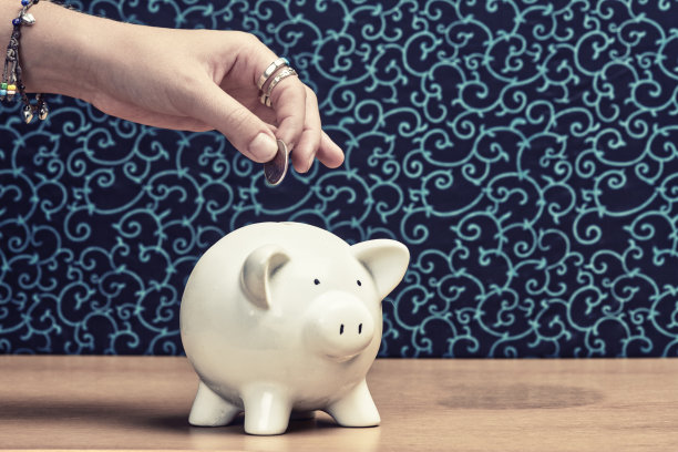 教育储蓄:年轻女子的手将硬币放入储蓄罐图片下载