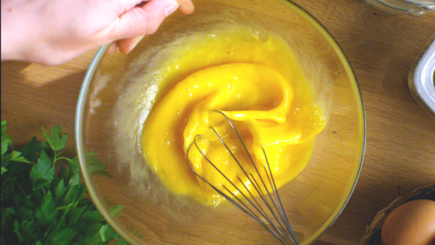 女人搅拌鸡蛋。在玻璃碗里打好鸡蛋，再加入空蛋壳。图片下载