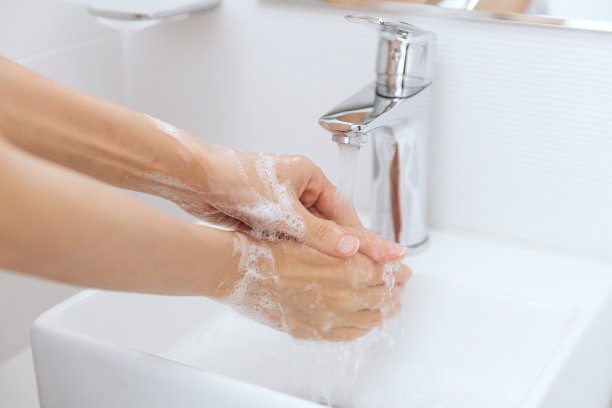 在水龙头下洗手。用肥皂洗手以预防冠状病毒的传播，防止冠状病毒在公共卫生间或公共卫生间的卫生传播。卫生概念手部细节图片下载