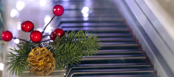 横幅与钢琴键与金色圆锥体，圣诞树树枝和红色浆果在散景背景。新年或圣诞音乐概念。图片下载