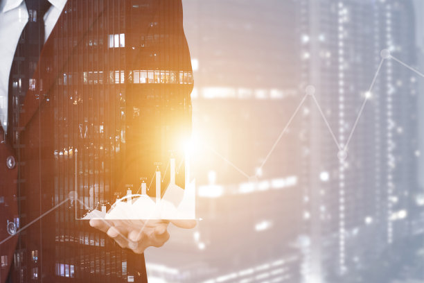 一个年轻商人和一个城市的双重曝光使用平板电脑和手持图形显示财务状况和业务增长的夜晚城市背景。图片下载