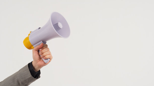 这名男子的手拿着扩音器，身穿白色背景的灰色西装。“t图片下载