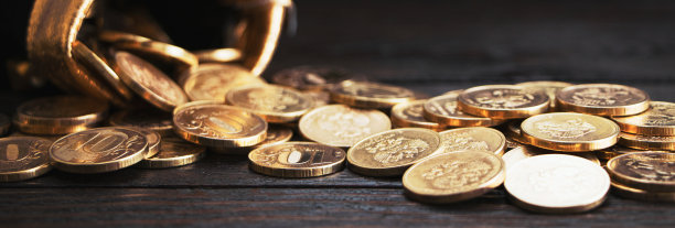 木制背景上有金币的袋子。钱在一个黑色的袋子里。寻宝游戏。一个有钱的钱包。钱包里有金币。图片下载