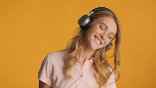 漂亮的金发女孩戴着耳机开心地听着新歌图片下载